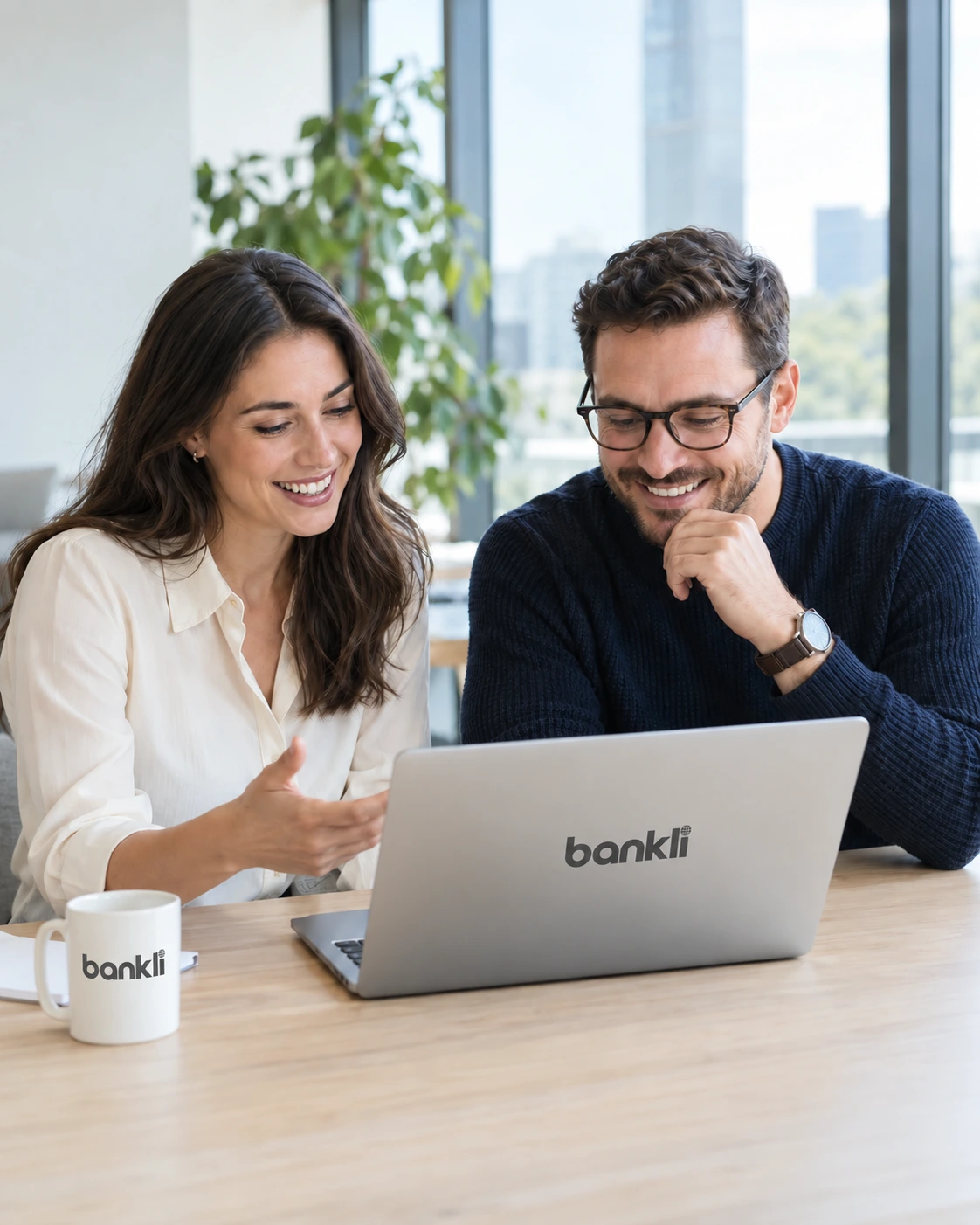 Two people discussing their business with a Bankli-branded laptop and mug